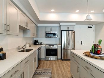 A modern kitchen with stainless steel appliances and wooden flooring.